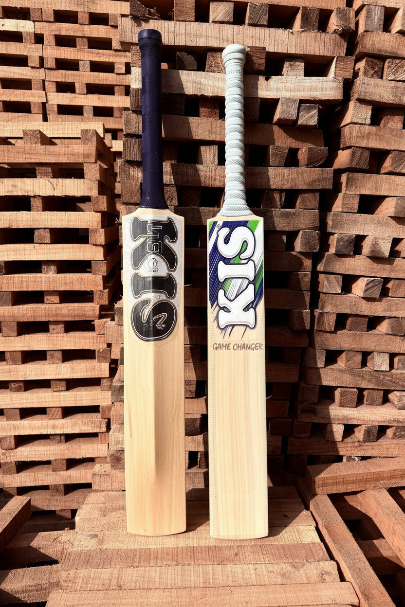 Two hard hitting cricket bats leaning against a stack of wooden pallets.