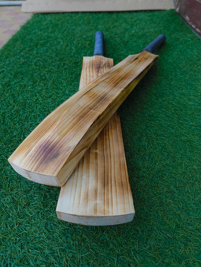 Two wooden hard tennis cricket bats on a green grass-like surface